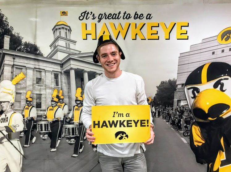 Tyler Bell holding an "I'm a Hawkeye!" sign