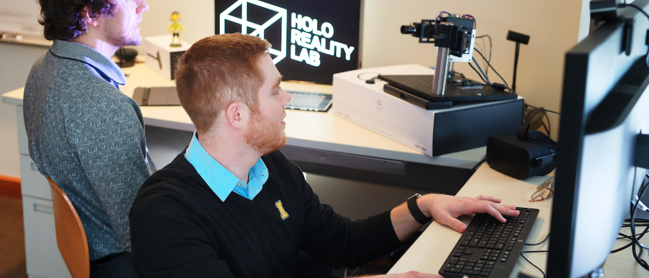 Tyler Bell works with a student in the lab