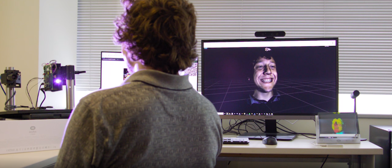 A person sitting in front of cameras and computer monitors
