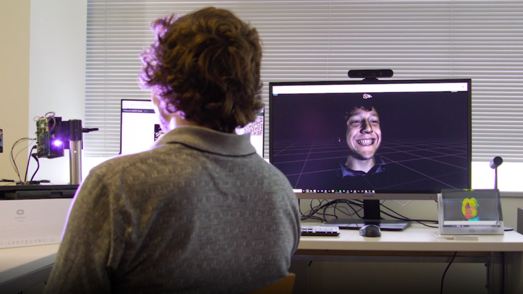 A person sitting in front of cameras and computer monitors